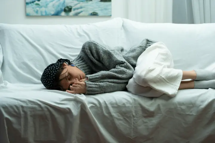 Femme endormie sur un canapé, la tête sur un coussin
