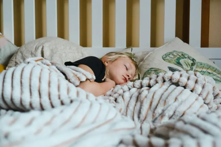 Petite fille endormie dans un lit, sous une couverture